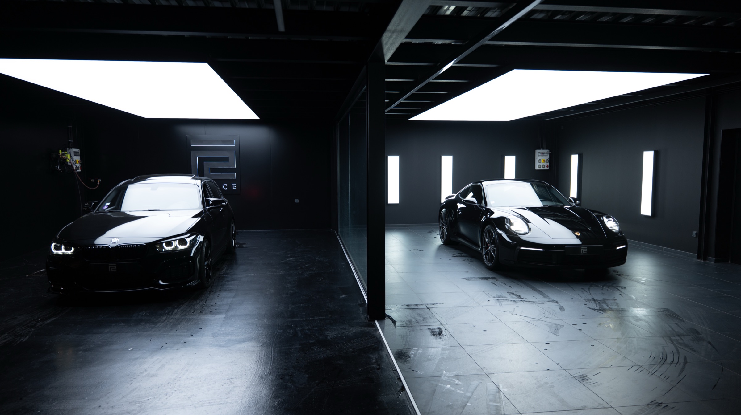 Vue large de l'atelier REYCE à La Mulatière, avec une BMW et une Porsche 911 réparties dans deux baies