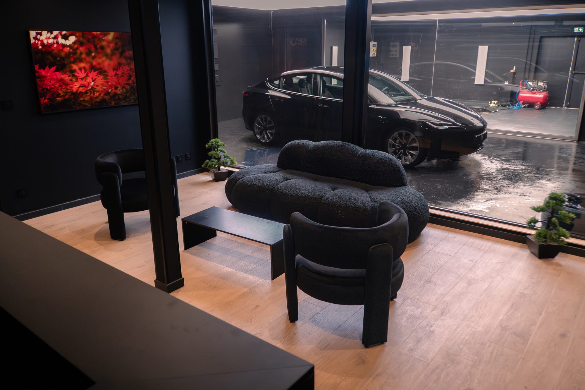 Lounge client de l’atelier REYCE, avec une Tesla visible à travers la vitre